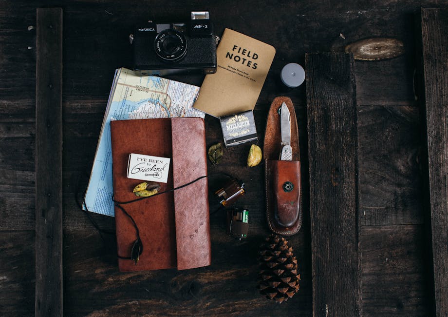 Overhead of vintage photo camera near leather notebook with map and camera roll near knife and cone placed on table