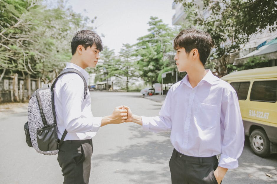 Two young men greeting each other with a handshake outdoors, conveying friendship and connection.