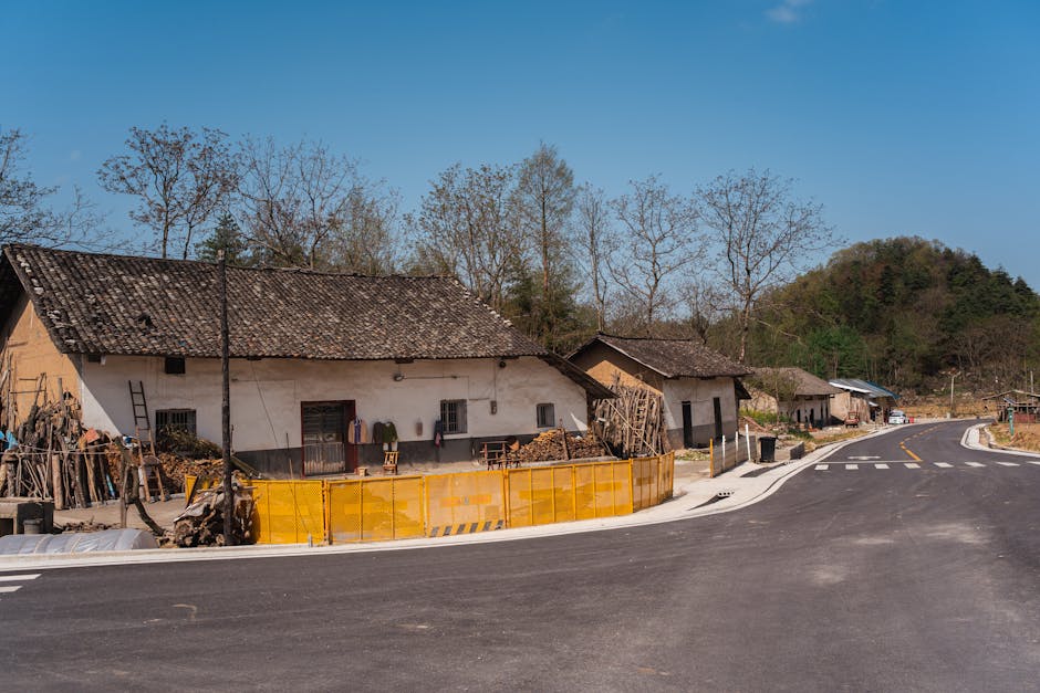 Scenic view of a traditional mountain village with rustic houses and a winding road under a clear blue sky.